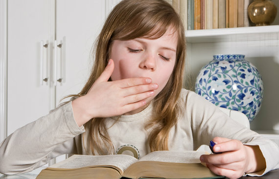 young girl yawning while reading a book that is too easy for her reading level
