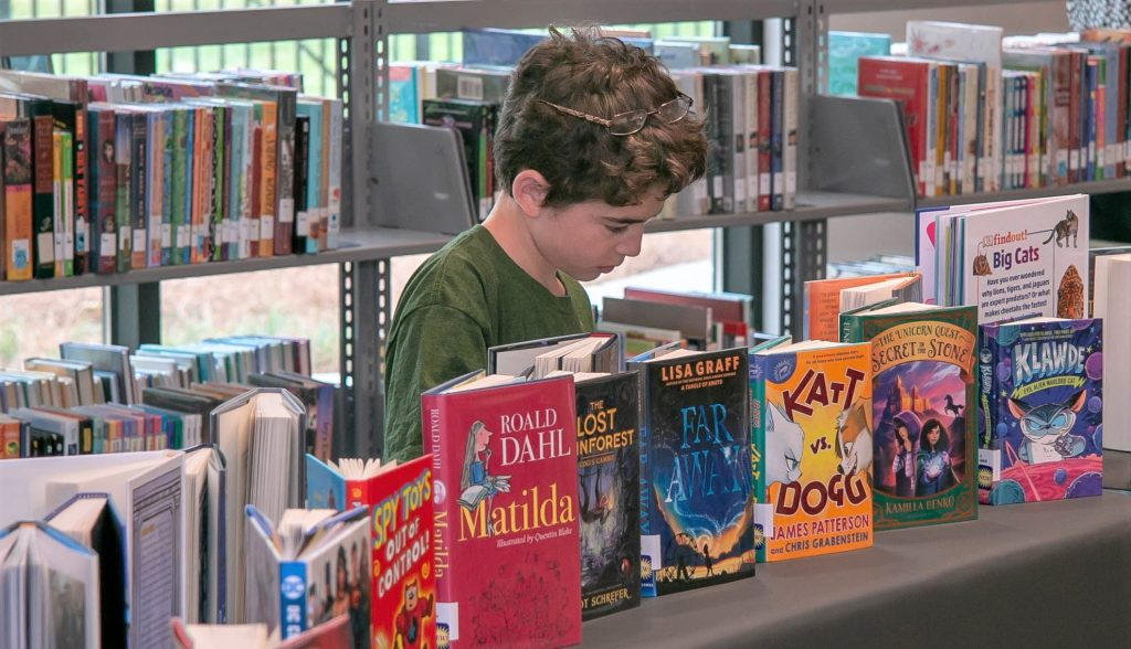 child choosing own books at library to overcome hatred of reading