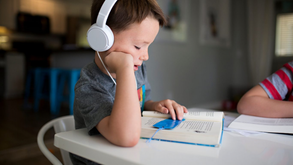 child listening to audiobook with headphones as strategy for reluctant reader who hates reading