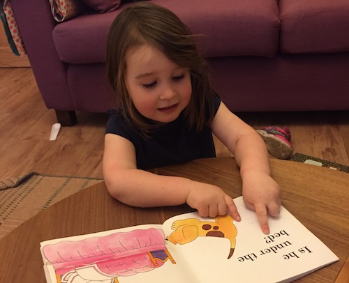 Child looking for phonics patterns while reading a book