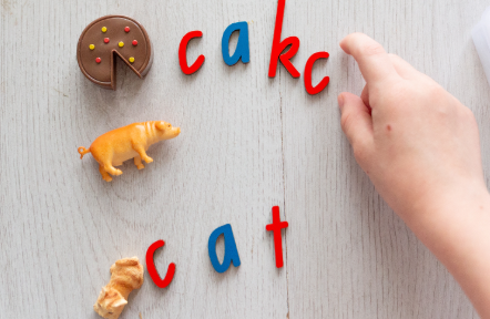 Children practicing letter sounds with word cards
