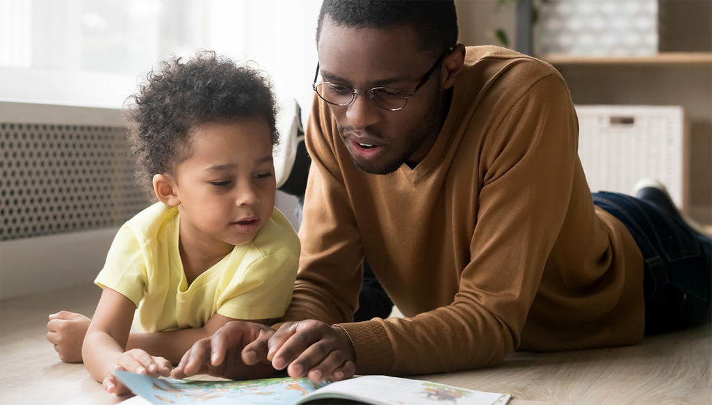 Parent helping a young child practice reading a book at home