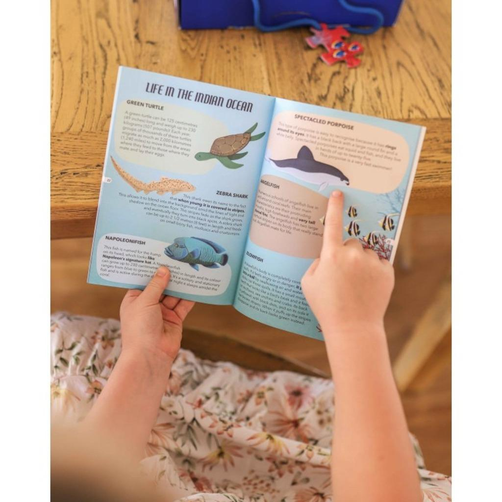 A child writing animal facts in a notebook beside a nonfiction book
