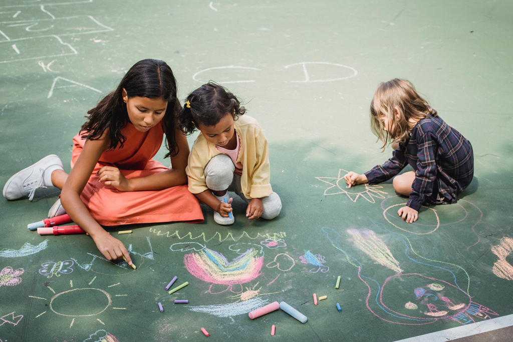 Children creating a colorful drawing with chalk