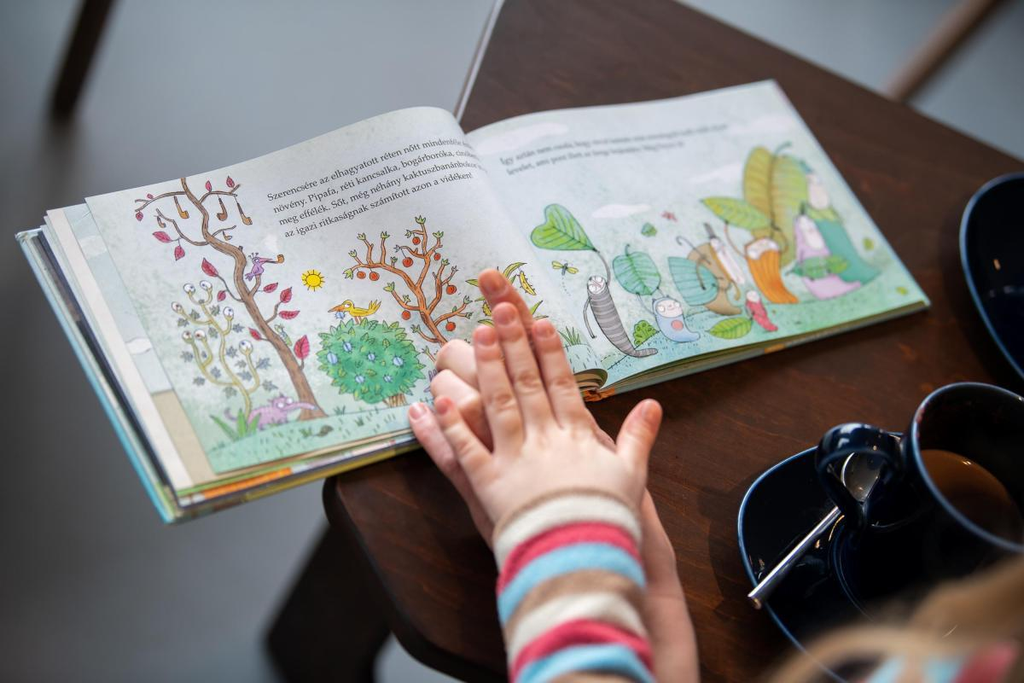Hands turning the pages of an illustrated children's book during a picture walk
